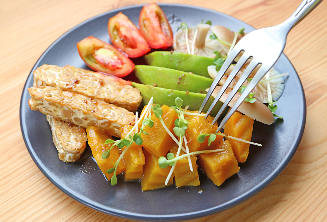 A Plate of Pan fried Tempeh Colorful Vegetables Salad Garnished with Daikon Sprouts
